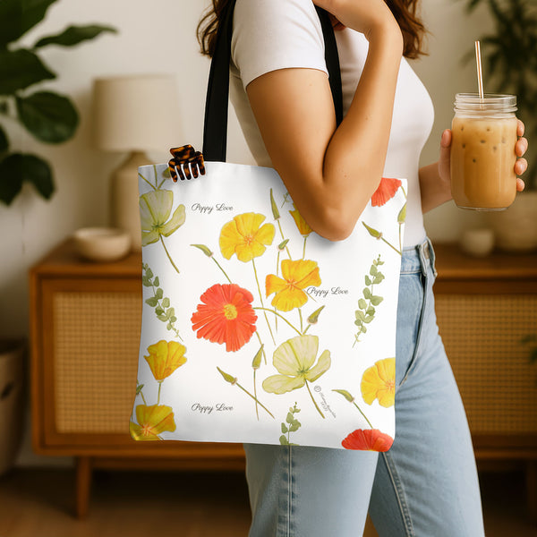 Person holding a tote bag with floral design and a drink in a home setting